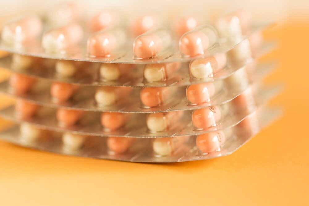 Stack of antibiotic capsules in blister pack over the yellow background